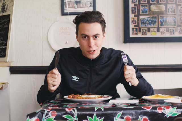An actor playing the part in the 2017/18 home kit trailer holds a knife and fork in a cafe.